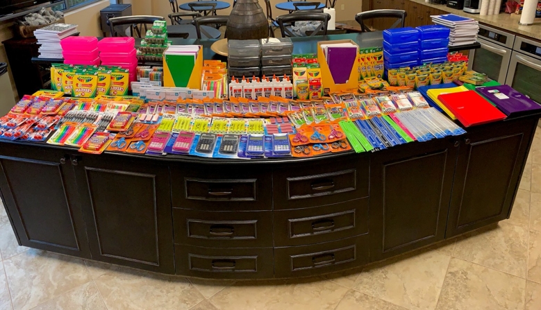 Table filled with school supplies for donation to Houston Children's Charity